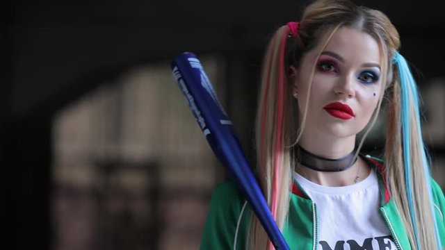 Unusual woman with fantastic makeup and unconventional hairstyle holding baseball-bat