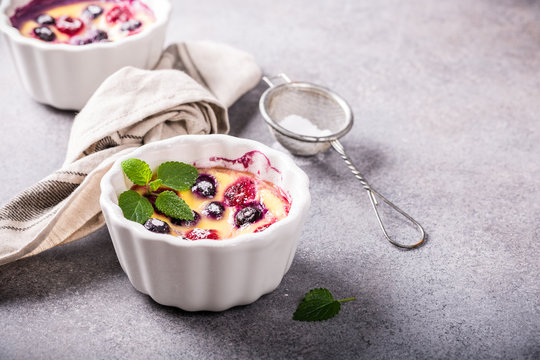 Berry clafouti. Traditional french sweet fruit dessert clafoutis with raspberries and blueberries on gray concrete background. Healthy gluten free food concept with copy space.