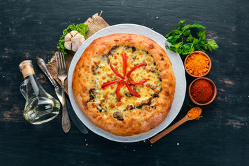 Khachapuri with cheese, mushrooms and paprika. On the old wooden background. Free space for text. Top view.