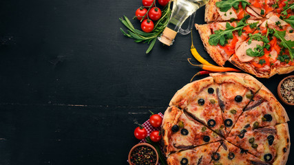 A set of pizza. On a black wooden background. Free space for text. Top view.