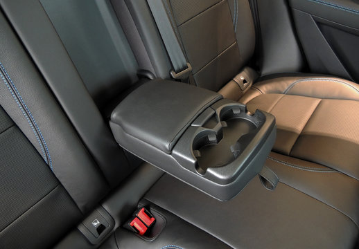 Leather trimmed folding armrest with cup holders in rear seats inside a vehicle