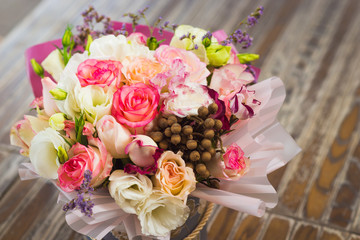 bouquet of multicolored roses decorated in a box on a wooden background