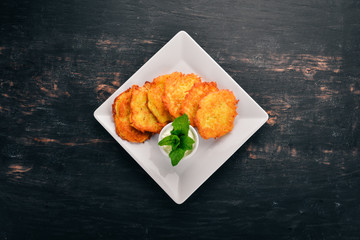 Potato cakes with sour cream. Potato pancakes. Ukrainian cuisine. On the old wooden background. Free space for text. Top view.