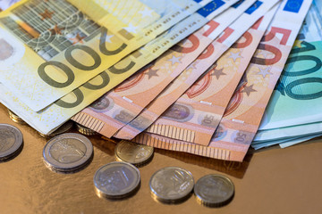 euro coin and banknotes isolated on gold
