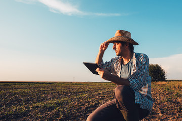 Farmer agronomist with tablet computer in bare empty field - obrazy, fototapety, plakaty