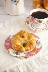 A Freshly Baked Buttery Croissant Laid on the Table for Breakfast with Hot Black Coffee
