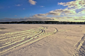 Snowy surface of the Volga River in winter with snowmobile tracks. Kostroma, Russia.
