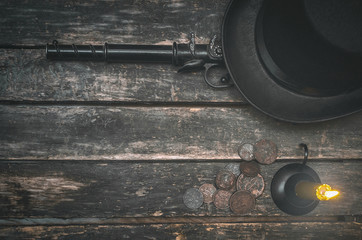 Musket gun, money, bowler hat and burning candle on wooden table background.