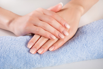 Obraz na płótnie Canvas Ombre french nails on woman hands on blue gently towel in beauty salon. Manicure and beauty concept