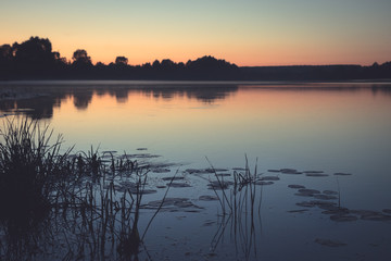 Fototapeta premium Twilight dark lake rustic countryside tranquil scenery landscape sunset with pink sky and tranquil water mirror reflections in vintage style