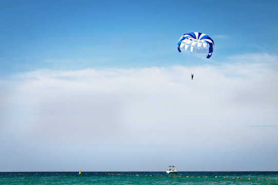 Water sport, active sport. Blue parachute hovers above the Mediterranean Sea. Parasailing also known as parascending or parakiting.