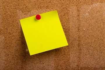 Yellow Sticky Note with Pin on a Bulletin Board