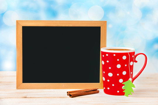 
A board for notes with a red mug on a wooden table, a festive background
