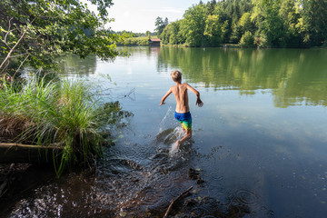 Boy having bath in wood lake