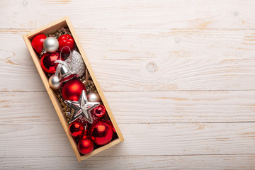 Box with silver and red christmas gifts on white wooden background. Top view. Copy space