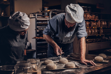 Cooking master class in bakery. Chef with his assistant showing ready samples of baking test in kitchen.