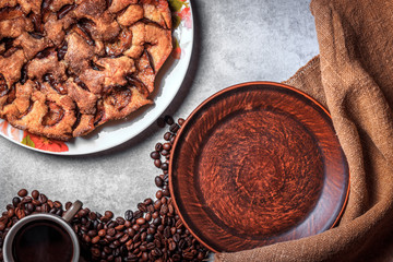 Homemade pie, blank rustic plate, coffee beans on sackcloth. Concrete background. Top view. Mockup