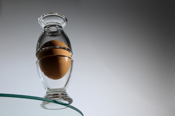Jajko kurze w kieliszku na krawędzi szklanych mebli.
