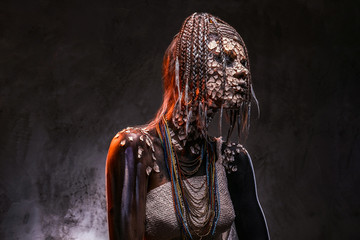 Portrait of a scary African shaman female with a petrified cracked skin and dreadlocks. Make-up...