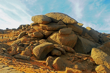 A large mound of boulders against a pale blue sky