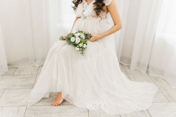 Plakat Belly of a pregnant girl in a beautiful dress and a bouquet of flowers