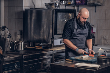 Brutal chef dressed in uniforms preparing sushi in the kitchen.
