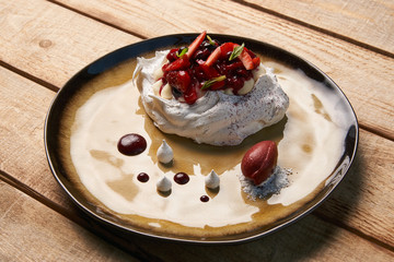 Dessert Pavloca cake with fruits and berry ice cream on wooden table background, close-up