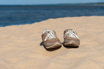 Pair of old shoes at sandy beach of Baltic sea, Latvia