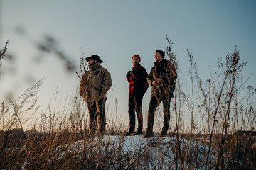 Four friends stand on a hill during a beautiful sunset. Winter trip. Relax and meeting friends. Friendship and longevity.