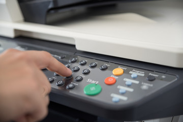 Office worker works with a multi-function device and sets the number of copies to print