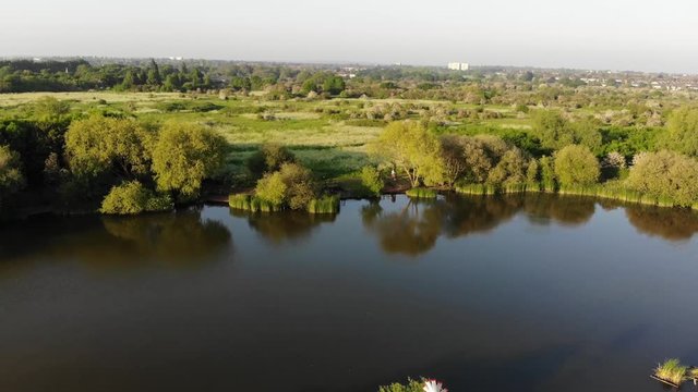 Flying over the wind turbine in the middle of the Bardag Lake in the Eastbrookend Country Park at sunset.