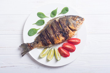 Fried fish dorado with lime , tomatoes and spinach