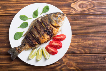 Fried fish dorado with lime , tomatoes and spinach