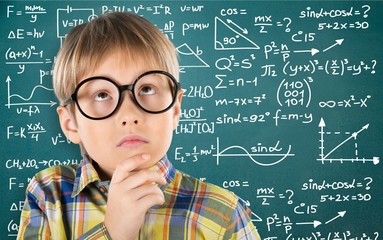 Cute little schoolgirl in glasses on blackboard