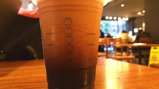 Upwards tilting reveal of a foamy nitro cold brew coffee at a Starbucks venue