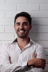 young white man wearing social outfit standing and posing in front of white brick wall