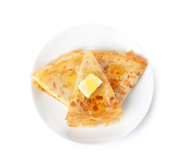 Tasty thin folded pancakes with butter and honey on plate against white background, top view