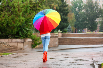 Young woman with bright umbrella under rain outdoors