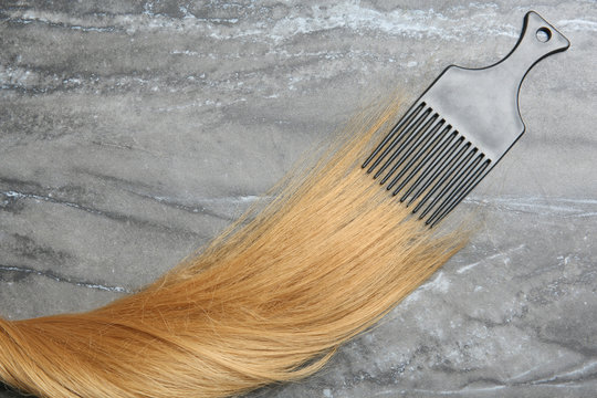 Flat lay composition with strand of hair and comb on grey background. Space for text