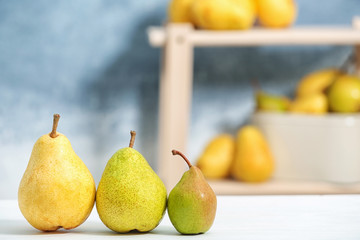 Fresh ripe pears on light table against blurred background. Space for text