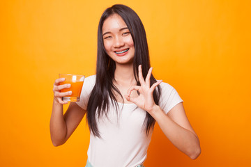 Young Asian woman show OK drink orange juice.