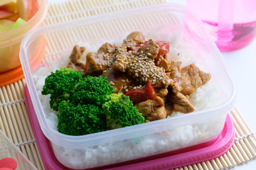 Asian style school lunch box served with sesame pork and broccoli