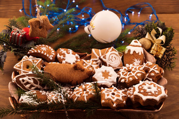 Dish with festive pastries in the form of cookies, decorated with icing sugar, Christmas decorations, wooden background.