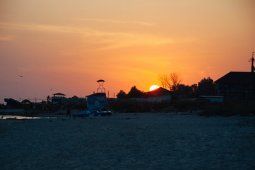 Naklejka premium A warm orange sunset on the shore of the ocean, the sea, draws silhouettes in the sunset of a summer