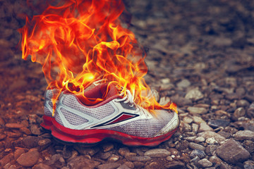 Burning Old Sneakers Or Shoes On Stone Surface Or Pebble Beach. Concept Of Passing Youth Or End Of...