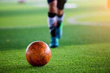 Soccer player put blue sport shoes shoot ball on artificial turf.