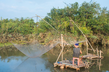  Nakhon Phanom, Thailand - 14 September 2018 : old woman catch fish with flattering on the rive