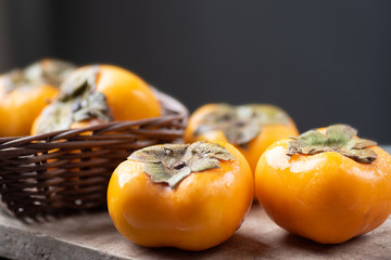 Ripe persimmon fruit in a basket on wooden background