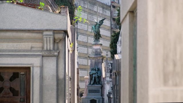 Angel and Three men holding flag mausoleum statue in La Recoleta Cementery at daytime long shot