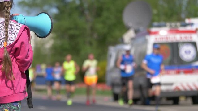 Girl cheering runners by megaphone in 4k slow motion 60fps